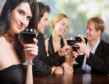 Dressed up mid-aged people drinking a dark liquid in wine glasses