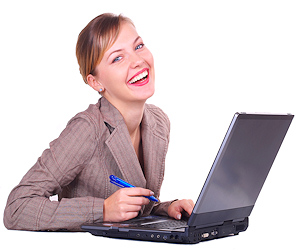 Lady sitting in front of a laptop with a blue pen in her hand laughing with a giant smile
